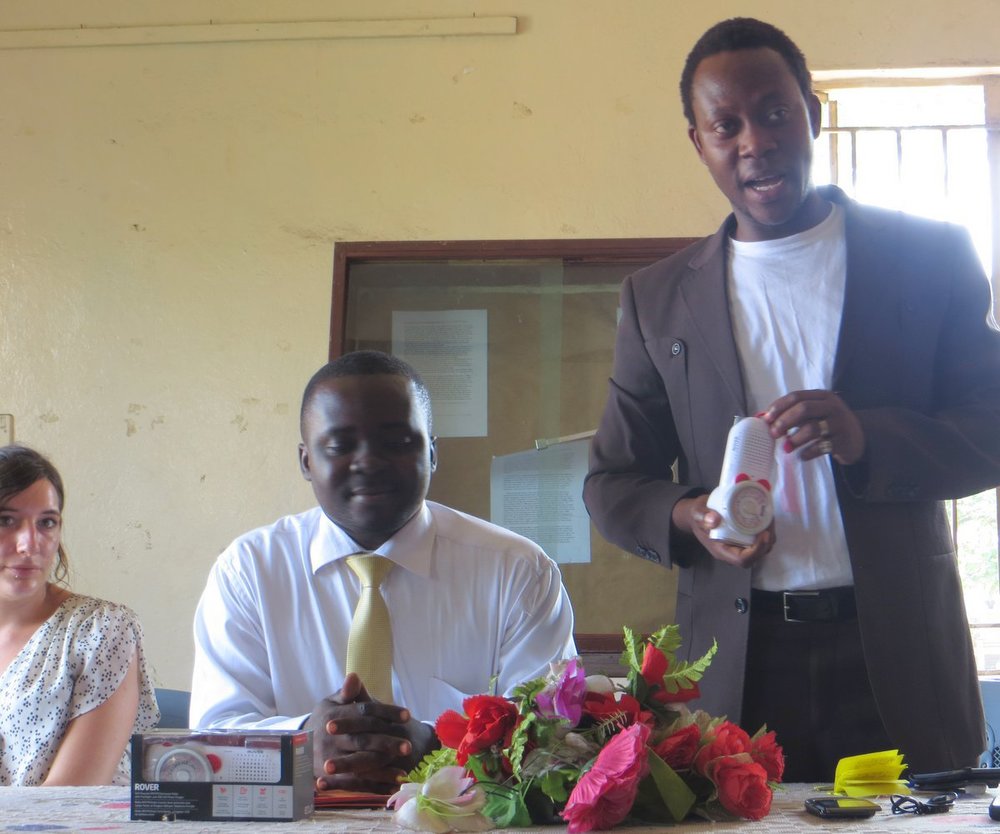 In a donation ceremony at the National Museum in Freetown, ACIPP’s Executive Director Simon Tsike-Sossah (standing) discusses radios donated by Ears To Our World. Seated next to Mr. Tsike-Sossah is Ibrahim Tommy, CARL’s executive director; seated at far left is Imma Mäder, ACIPP’s director for marketing and recruitment. (Photo by Kelsey Lizotte for ACIPP West Africa).